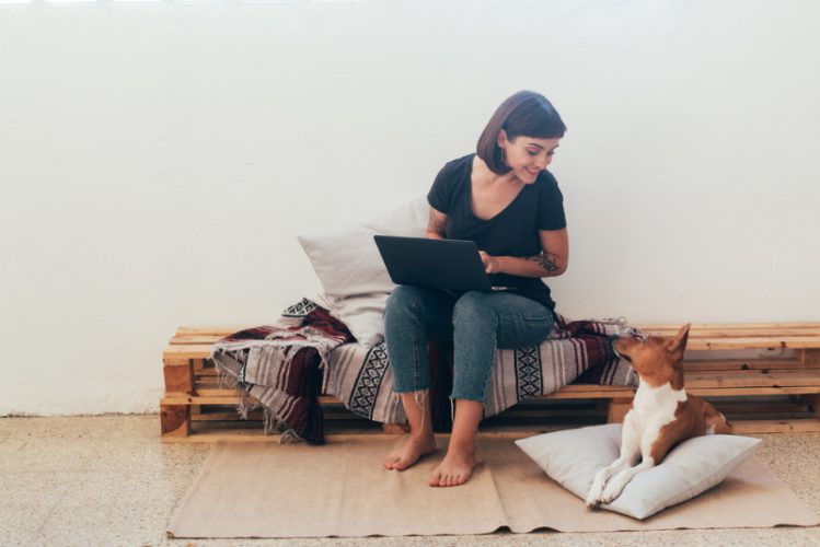 パソコンを操作している女性と、そばに座る愛犬の様子