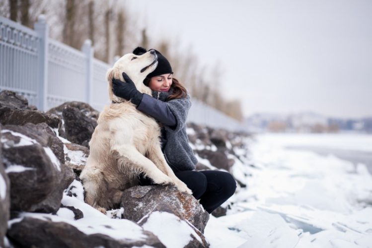 飼い主と犬が雪の中で身を寄せ合っている様子